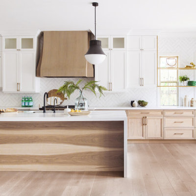 Transitional l-shaped medium tone wood floor and brown floor open concept kitchen photo in San Diego with an undermount sink, recessed-panel cabinets, light wood cabinets, white backsplash, stainless steel appliances, an island and white countertops