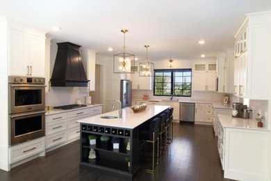 Example of a huge classic u-shaped ceramic tile and brown floor kitchen design in Minneapolis with an undermount sink, flat-panel cabinets, white cabinets, quartz countertops, white backsplash, stone slab backsplash, stainless steel appliances, an island and white countertops