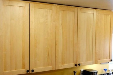 Idées déco pour une cuisine en U et bois clair avec un placard avec porte à panneau encastré et un plan de travail en granite.