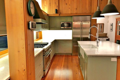 Mid-sized trendy medium tone wood floor kitchen photo in Seattle with a farmhouse sink, shaker cabinets, distressed cabinets, quartzite countertops, white backsplash, subway tile backsplash, stainless steel appliances and an island