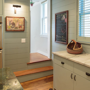 Large farmhouse eat-in kitchen photos - Inspiration for a large country medium tone wood floor eat-in kitchen remodel in New York with a farmhouse sink, flat-panel cabinets, green cabinets, stainless steel appliances, an island, marble countertops, beige backsplash and stone slab backsplash
