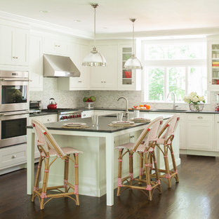 Inspiration for a large transitional l-shaped dark wood floor open concept kitchen remodel in New York with an undermount sink, shaker cabinets, white cabinets, granite countertops, gray backsplash, stainless steel appliances and an island