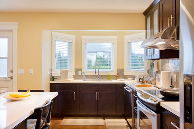 Photo of a medium sized contemporary l-shaped open plan kitchen with a submerged sink, raised-panel cabinets, dark wood cabinets, quartz worktops, white splashback, glass tiled splashback, stainless steel appliances, medium hardwood flooring and an island.