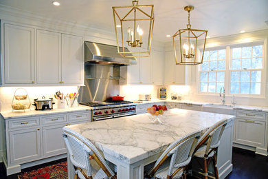 Bild på ett avskilt, stort lantligt l-kök, med en rustik diskho, luckor med infälld panel, vita skåp, marmorbänkskiva, vitt stänkskydd, stänkskydd i tunnelbanekakel, rostfria vitvaror, mörkt trägolv och en köksö