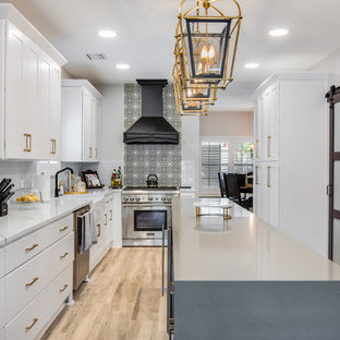 Large transitional kitchen remodeling - Inspiration for a large transitional l-shaped porcelain tile and brown floor kitchen remodel in Houston with a farmhouse sink, shaker cabinets, white cabinets, quartzite countertops, glass tile backsplash, stainless steel appliances, an island, white countertops and multicolored backsplash