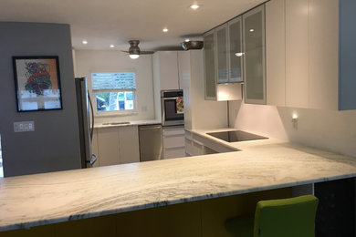 Foto på ett avskilt, stort funkis u-kök, med släta luckor, vita skåp, marmorbänkskiva, en halv köksö, en undermonterad diskho, rostfria vitvaror, linoleumgolv och vitt golv