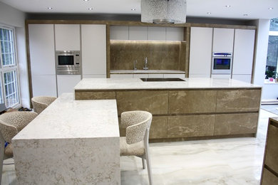 Design ideas for a large contemporary open plan kitchen in London with a submerged sink, flat-panel cabinets, brown cabinets, marble worktops, brown splashback, marble splashback, stainless steel appliances, ceramic flooring, multiple islands and white floors.