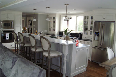 Example of a mid-sized transitional galley medium tone wood floor eat-in kitchen design in Boston with an undermount sink, recessed-panel cabinets, white cabinets, marble countertops, black backsplash, stone tile backsplash, stainless steel appliances and an island
