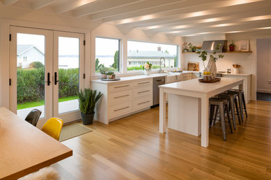 Eat-in kitchen - contemporary l-shaped eat-in kitchen idea in Boston with a farmhouse sink, shaker cabinets, white cabinets, quartz countertops, white backsplash, porcelain backsplash, stainless steel appliances, an island and white countertops
