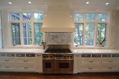 Example of a mid-sized arts and crafts u-shaped medium tone wood floor and brown floor open concept kitchen design in San Francisco with an undermount sink, recessed-panel cabinets, white cabinets, marble countertops, white backsplash, stone slab backsplash, paneled appliances and an island