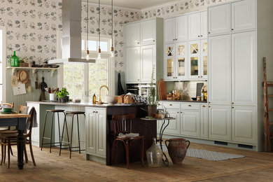 Example of a large transitional galley medium tone wood floor eat-in kitchen design in Gothenburg with green cabinets, white backsplash, porcelain backsplash, an island and raised-panel cabinets