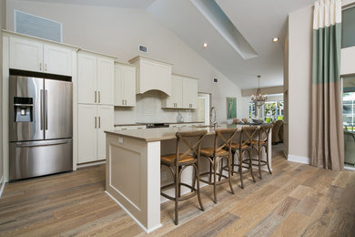 Example of a mid-sized beach style single-wall medium tone wood floor kitchen design in Tampa with shaker cabinets, white cabinets, stainless steel appliances and an island