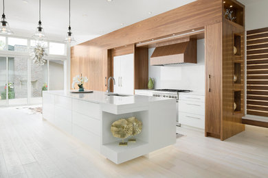 Design ideas for a large contemporary galley open plan kitchen in Calgary with a submerged sink, flat-panel cabinets, medium wood cabinets, engineered stone countertops, white splashback, ceramic splashback, stainless steel appliances, light hardwood flooring and an island.