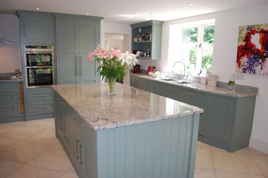 Photo of a large contemporary kitchen/diner in Sussex with a double-bowl sink, shaker cabinets, green cabinets, granite worktops, stainless steel appliances and an island.