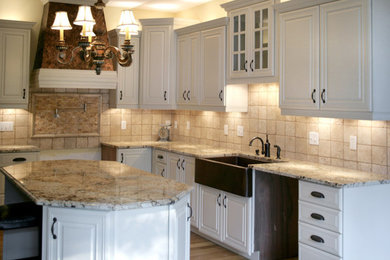 Inspiration for a large timeless u-shaped medium tone wood floor kitchen remodel in Atlanta with a farmhouse sink, raised-panel cabinets, white cabinets, granite countertops, stone tile backsplash and an island