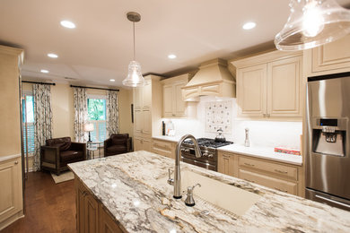 Example of a large transitional galley medium tone wood floor and brown floor eat-in kitchen design in Atlanta with an undermount sink, beaded inset cabinets, beige cabinets, granite countertops, white backsplash, porcelain backsplash, stainless steel appliances and an island