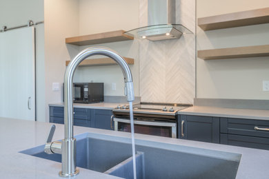 Example of a mid-sized minimalist single-wall open concept kitchen design in Vancouver with an undermount sink, shaker cabinets, blue cabinets, quartz countertops, white backsplash, porcelain backsplash, stainless steel appliances, an island and gray countertops