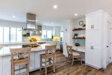 Example of a mid-sized transitional l-shaped medium tone wood floor and brown floor open concept kitchen design in Los Angeles with shaker cabinets, white cabinets, quartz countertops, an island, white countertops, an undermount sink, blue backsplash, glass tile backsplash and stainless steel appliances