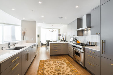 Example of a mid-sized trendy medium tone wood floor and brown floor open concept kitchen design in Vancouver with quartz countertops, gray backsplash, marble backsplash, an undermount sink, flat-panel cabinets, gray cabinets, stainless steel appliances and a peninsula