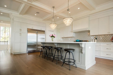 Example of a large transitional l-shaped vinyl floor eat-in kitchen design in Vancouver with an undermount sink, shaker cabinets, white cabinets, gray backsplash, glass tile backsplash, stainless steel appliances and an island
