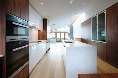 Example of a mid-sized trendy galley medium tone wood floor eat-in kitchen design in Vancouver with an undermount sink, flat-panel cabinets, dark wood cabinets, quartz countertops and an island