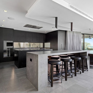Contemporary l-shaped kitchen in Perth with flat-panel cabinets, black cabinets, window splashback, black appliances, multiple islands, grey floor and grey benchtop.