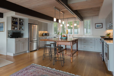 Large country u-shaped medium tone wood floor and brown floor open concept kitchen photo in Boston with shaker cabinets, white cabinets, an island, a farmhouse sink, marble countertops, multicolored backsplash, matchstick tile backsplash and stainless steel appliances