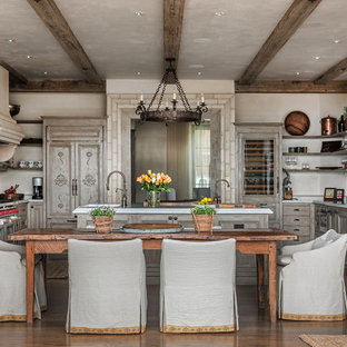 Diseño de cocina en U, mediterránea, con armarios con paneles con relieve, puertas de armario de madera clara, electrodomésticos con paneles, suelo de madera oscura y una isla