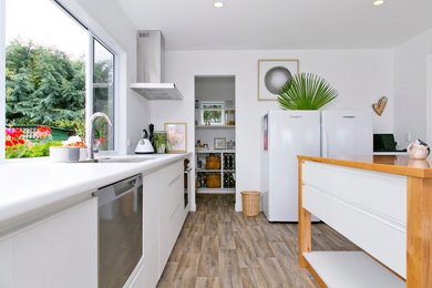 This is an example of a medium sized modern l-shaped enclosed kitchen in Other with white cabinets, stainless steel appliances, vinyl flooring, an island and white worktops.