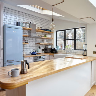 Imagen de cocina en U, campestre, pequeña, con fregadero sobremueble, armarios con paneles empotrados, puertas de armario blancas, encimera de madera, salpicadero blanco, salpicadero de azulejos tipo metro, electrodomésticos de colores, suelo de madera clara y península