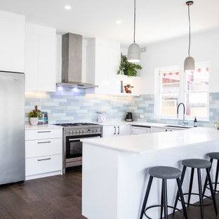 Design ideas for a large contemporary u-shaped open plan kitchen in Sydney with an undermount sink, white cabinets, quartz benchtops, multi-coloured splashback, subway tile splashback, stainless steel appliances, dark hardwood floors, with island, brown floor and white benchtop.