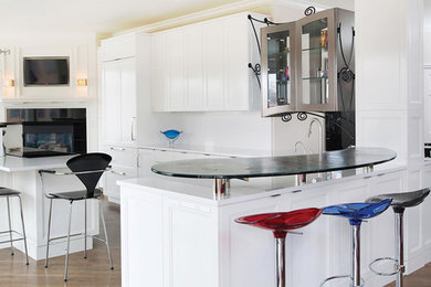 Imagen de cocina comedor actual con puertas de armario blancas, encimera de vidrio reciclado, suelo de madera en tonos medios y una isla