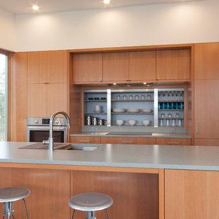 Inspiration pour une grand cuisine américaine linéaire minimaliste avec un évier 1 bac, un placard à porte plane, des portes de placard en bois brun, un plan de travail en quartz, un électroménager encastrable, un sol en liège et un îlot central.