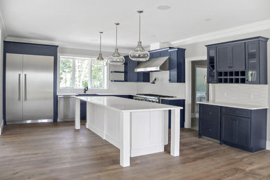 Large transitional l-shaped light wood floor and brown floor eat-in kitchen photo in Boston with a single-bowl sink, shaker cabinets, quartz countertops, white backsplash, stainless steel appliances, an island and white countertops