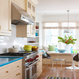 Beach style eat-in kitchen in New York with recessed-panel cabinets, beige cabinets, white splashback and turquoise benchtop.