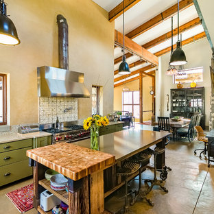 Foto de cocina urbana, abierta, con armarios estilo shaker, puertas de armario verdes, salpicadero beige, salpicadero con mosaicos de azulejos, electrodomésticos de acero inoxidable, suelo de cemento, una isla y suelo gris