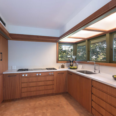 Inspiration for a small mid-century modern u-shaped medium tone wood floor and brown floor enclosed kitchen remodel in Los Angeles with an undermount sink, flat-panel cabinets, medium tone wood cabinets, solid surface countertops, white backsplash, paneled appliances, no island and white countertops