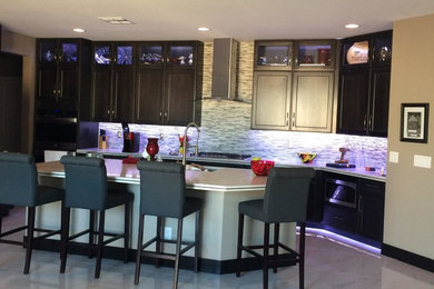 Mid-sized porcelain tile eat-in kitchen photo in Las Vegas with an undermount sink, shaker cabinets, brown cabinets, quartz countertops, mosaic tile backsplash, stainless steel appliances and an island