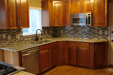 Small elegant l-shaped light wood floor enclosed kitchen photo in Cincinnati with a double-bowl sink, raised-panel cabinets, medium tone wood cabinets, granite countertops, multicolored backsplash, matchstick tile backsplash, stainless steel appliances and no island