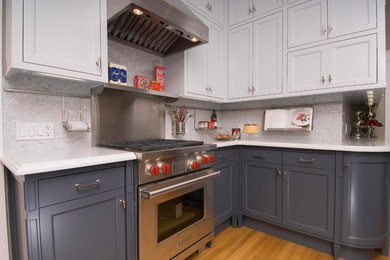 Mid-sized trendy l-shaped light wood floor eat-in kitchen photo in San Francisco with an undermount sink, shaker cabinets, blue cabinets, quartz countertops, gray backsplash, glass tile backsplash, stainless steel appliances and a peninsula
