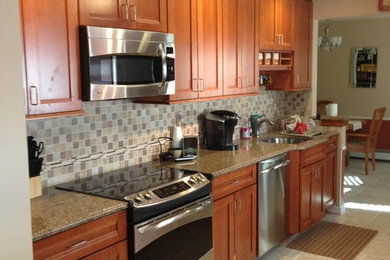 Mid-sized elegant galley porcelain tile eat-in kitchen photo in New York with an undermount sink, shaker cabinets, medium tone wood cabinets, ceramic backsplash and stainless steel appliances