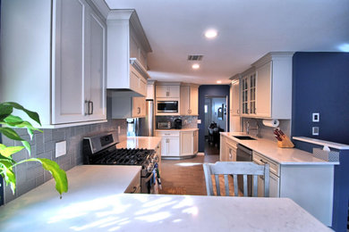 Example of a mid-sized classic galley slate floor and gray floor eat-in kitchen design in New York with an undermount sink, recessed-panel cabinets, gray cabinets, quartz countertops, gray backsplash, glass tile backsplash, stainless steel appliances, a peninsula and white countertops