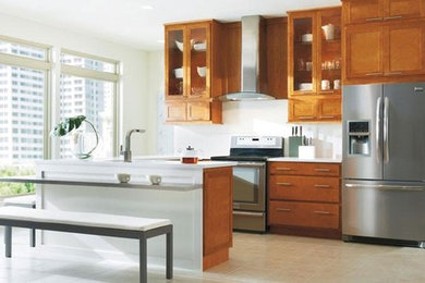 シアトルにある中くらいなコンテンポラリースタイルのおしゃれなキッチン (シェーカースタイル扉のキャビネット、中間色木目調キャビネット、白いキッチンパネル、シルバーの調理設備、ラミネートの床) の写真