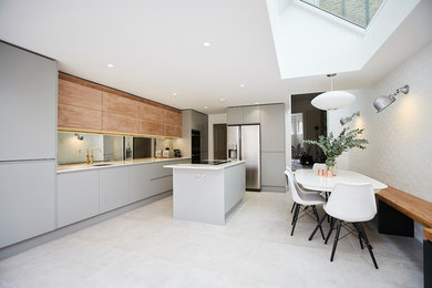Design ideas for a medium sized contemporary open plan kitchen in Sussex with an integrated sink, composite countertops, mirror splashback, integrated appliances, ceramic flooring, an island, grey floors and white worktops.