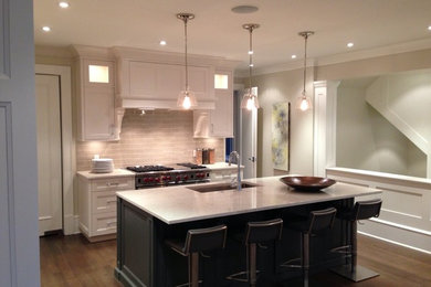 Photo of a medium sized traditional l-shaped kitchen in Vancouver with a submerged sink, recessed-panel cabinets, white cabinets, metro tiled splashback, stainless steel appliances, dark hardwood flooring, an island and brown floors.