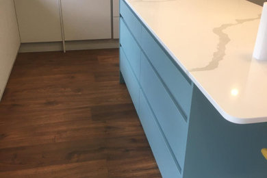 Medium sized contemporary l-shaped kitchen/diner in Other with a single-bowl sink, flat-panel cabinets, blue cabinets, quartz worktops, grey splashback, slate splashback, stainless steel appliances, laminate floors, an island and green worktops.