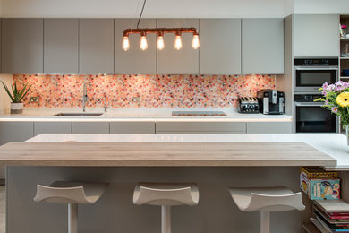 Inredning av ett modernt mellanstort linjärt kök, med en undermonterad diskho, släta luckor, grå skåp, marmorbänkskiva, flerfärgad stänkskydd, en halv köksö och grått golv