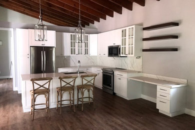 Example of a large trendy l-shaped eat-in kitchen design in Other with shaker cabinets, white cabinets, granite countertops, white backsplash, an island and white countertops