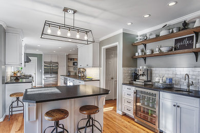 Mid-sized elegant galley light wood floor eat-in kitchen photo in Charlotte with a single-bowl sink, shaker cabinets, stainless steel cabinets, granite countertops, white backsplash, ceramic backsplash, stainless steel appliances and an island