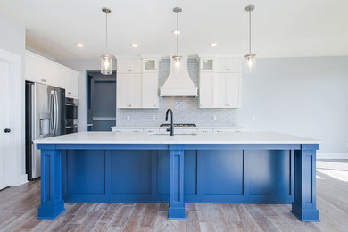 Inspiration for a mid-sized transitional u-shaped vinyl floor and brown floor eat-in kitchen remodel in Grand Rapids with an undermount sink, recessed-panel cabinets, white cabinets, quartzite countertops, white backsplash, subway tile backsplash, stainless steel appliances, an island and white countertops